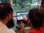 Two permaculture designers looking at permaculture design on a laptop screen.